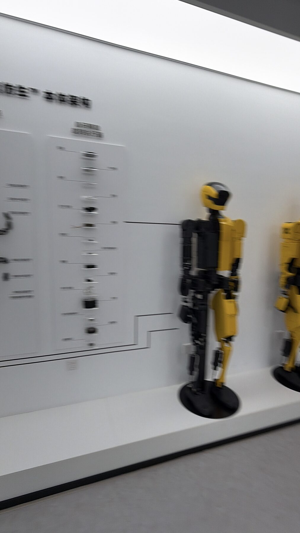 Robôs humanoides amarelos expostos com a ficha técnica na parede, em showroom na China