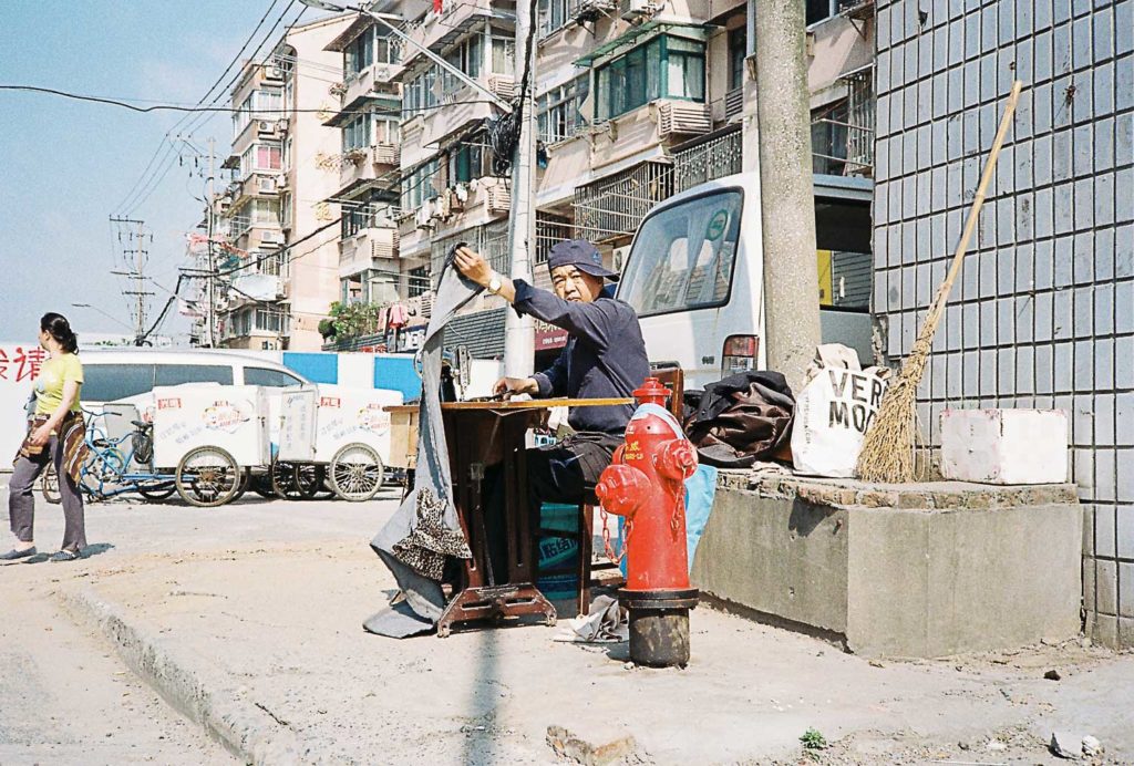 Homem costurando nas ruas de Xangai
