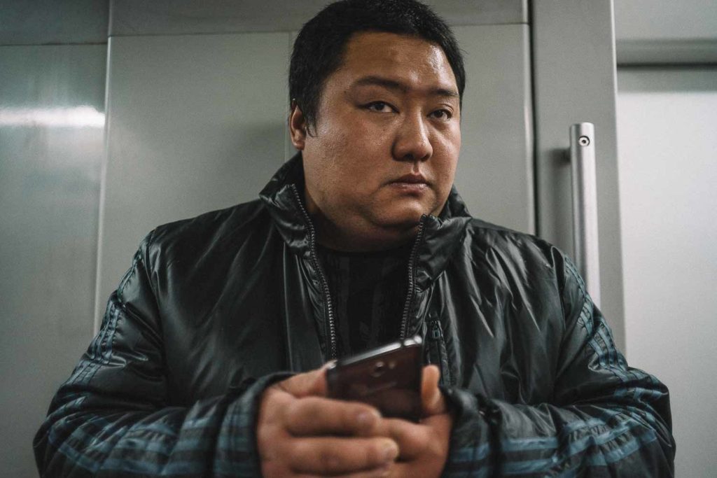 Homem chinês desconfiado com o seu celular na mão