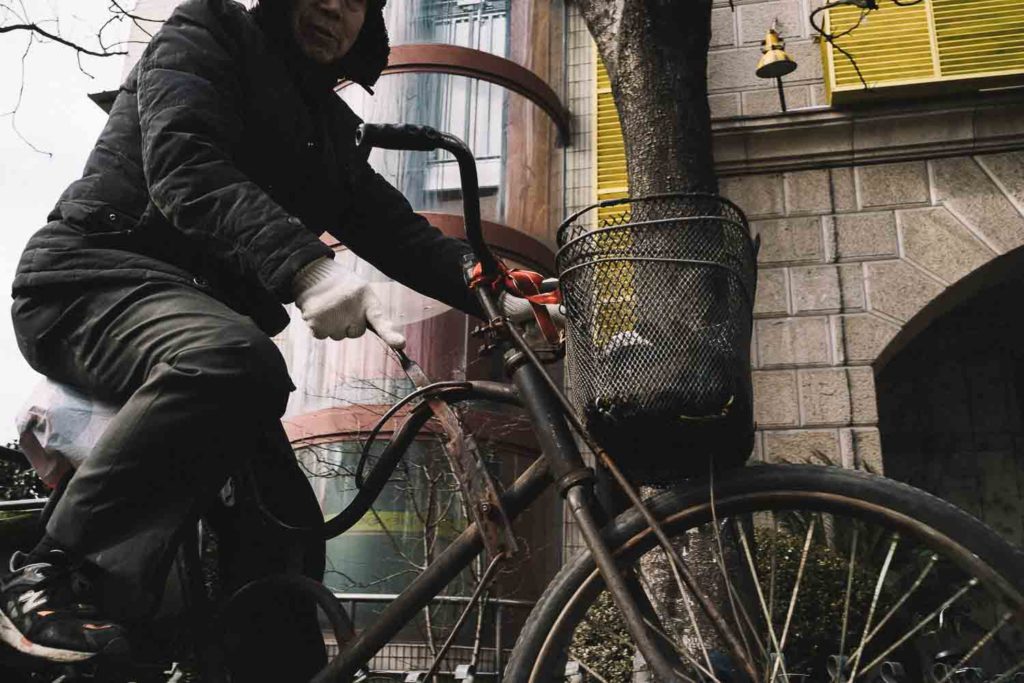 Chinês com bicicleta antiga no centro da cidade