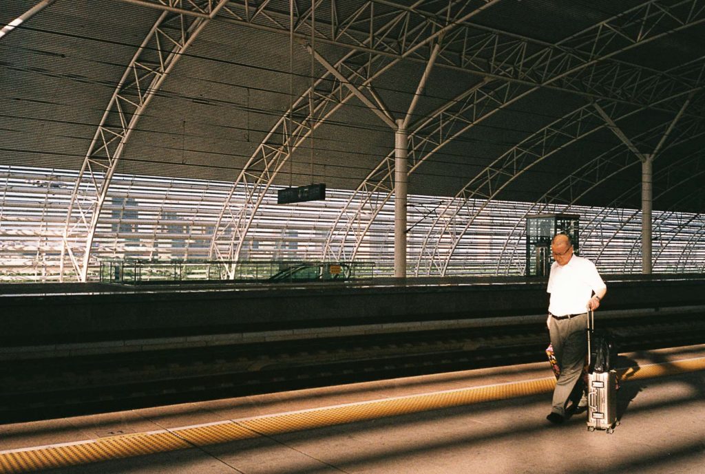 Homem caminhando em estação da China com mala