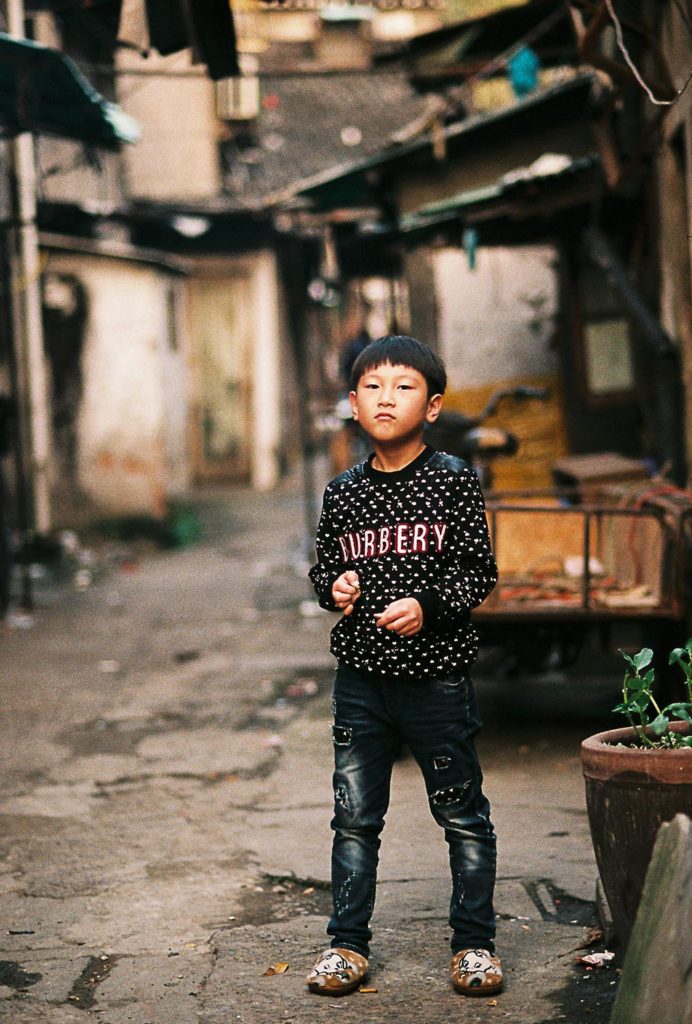 Criança chinesa com roupa da burberry em cidade antiga