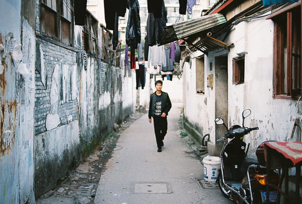 Homem caminhando em cidade de hutong em Pequim