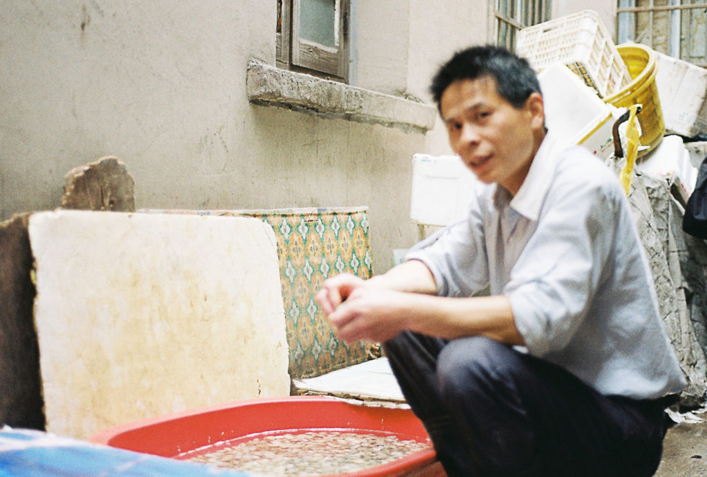 Homem chinês limpando molusco