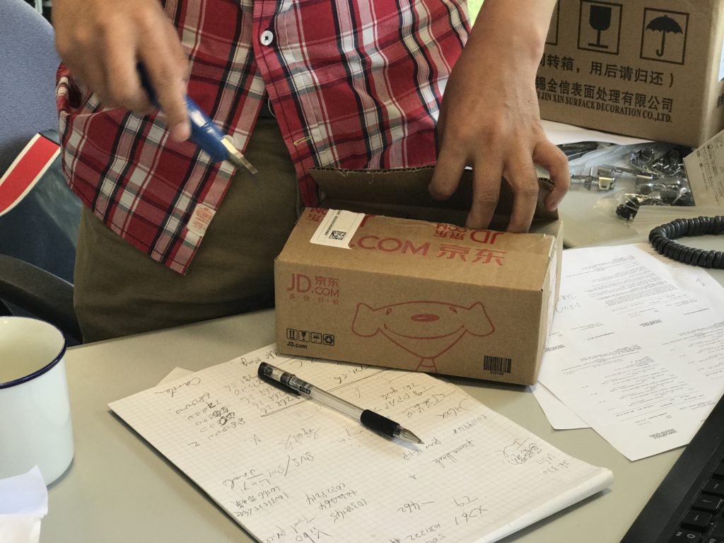 Compras online na China com JD Homem abrindo caixa de papelão com estilete