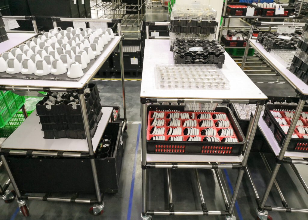 Guia completo para importar máquinas e equipamentos da China com sucesso: Bandejas de garrafas em carrinho em uma fábrica.