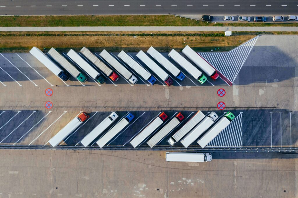 Vista aérea de caminhões estacionados em um estacionamento, mostrando a eficiência e organização da logística.