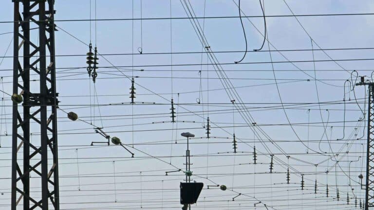 Close de uma rede de linhas de energia aéreas com estruturas de suporte contra um céu limpo, lembrando as conexões complexas encontradas nas vibrantes cidades da China.