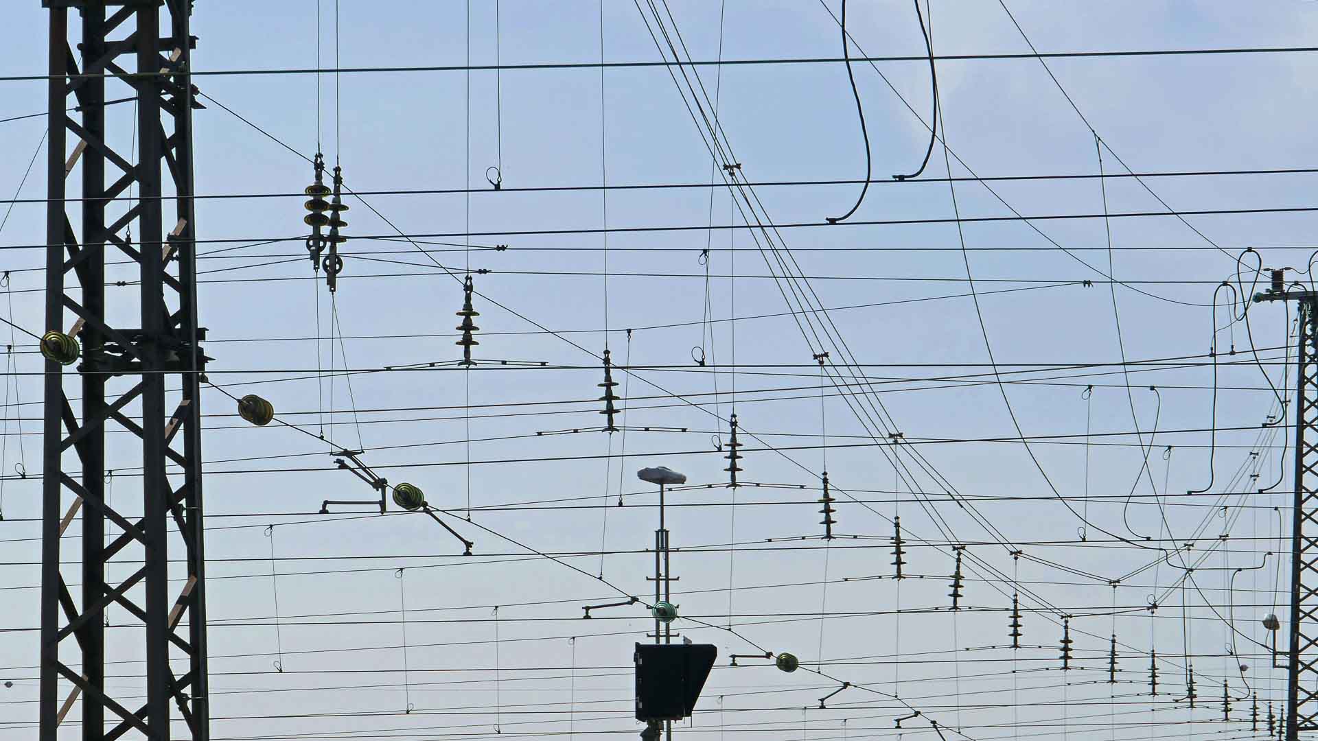 Close de uma rede de linhas de energia aéreas com estruturas de suporte contra um céu limpo, lembrando as conexões complexas encontradas nas vibrantes cidades da China.