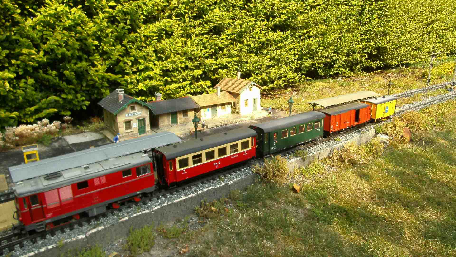 O conjunto de trens em miniatura, que lembra uma viagem panorâmica pela China, apresenta vários vagões coloridos em um trilho, passando por prédios em miniatura e vegetação exuberante, perfeito para inspirar sua próxima viagem.