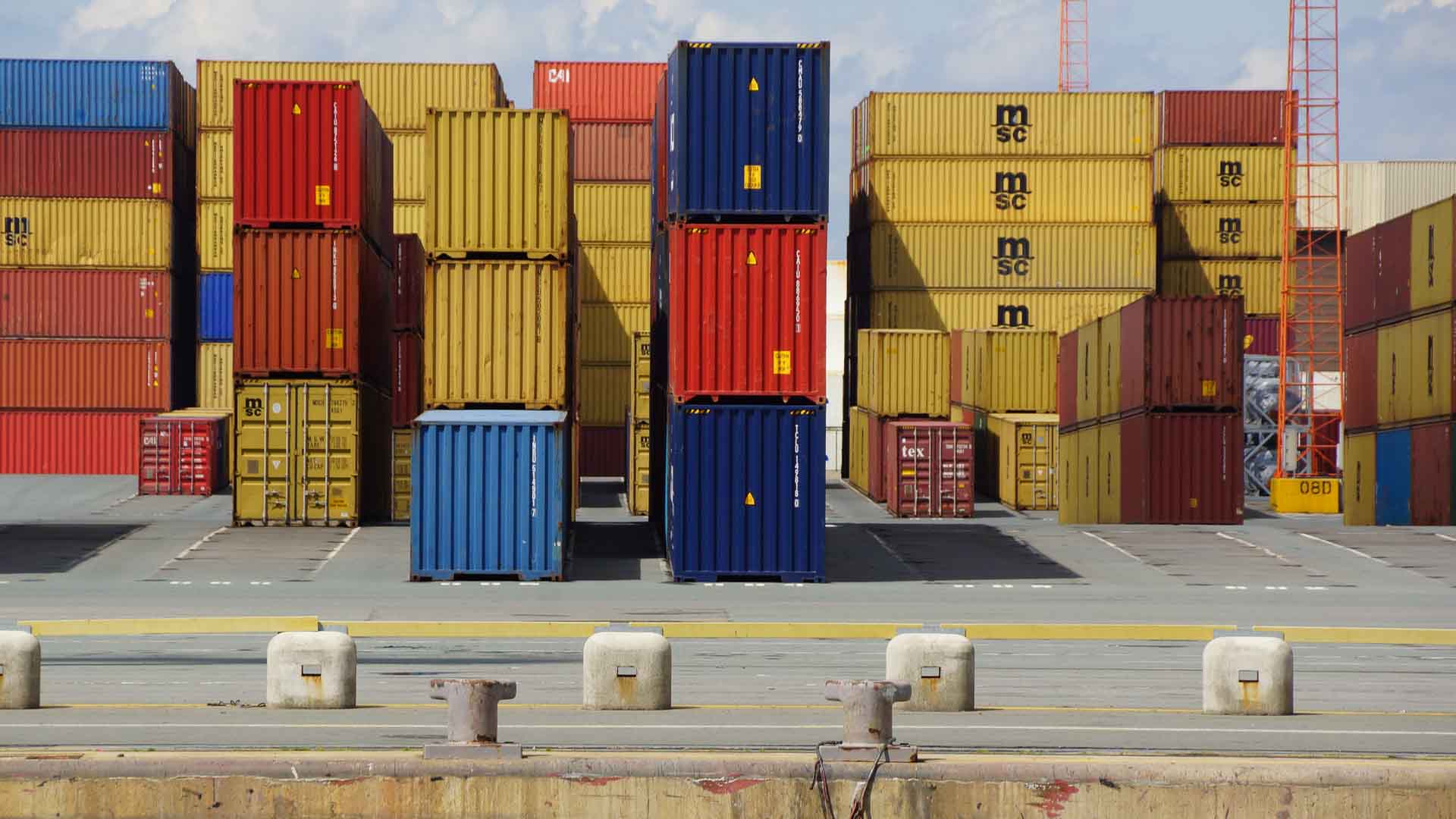 Pilhas de contêineres vibrantes em um porto movimentado, com guindastes imponentes ao fundo, sugerindo a tendência crescente de importar pelo Alibaba de forma fácil e eficiente.