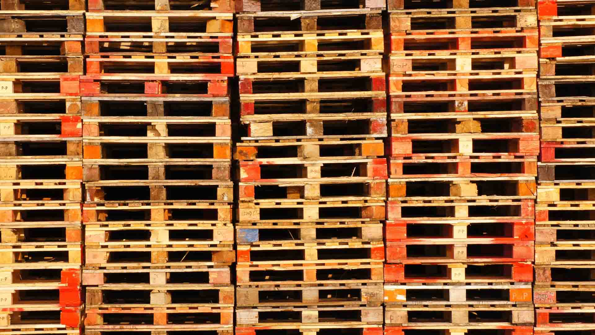 Pilhas de paletes de madeira estão dispostas de forma organizada, exibindo vários tons de marrom e vermelho, perfeitos para quem quer vender mais em mercados populares.