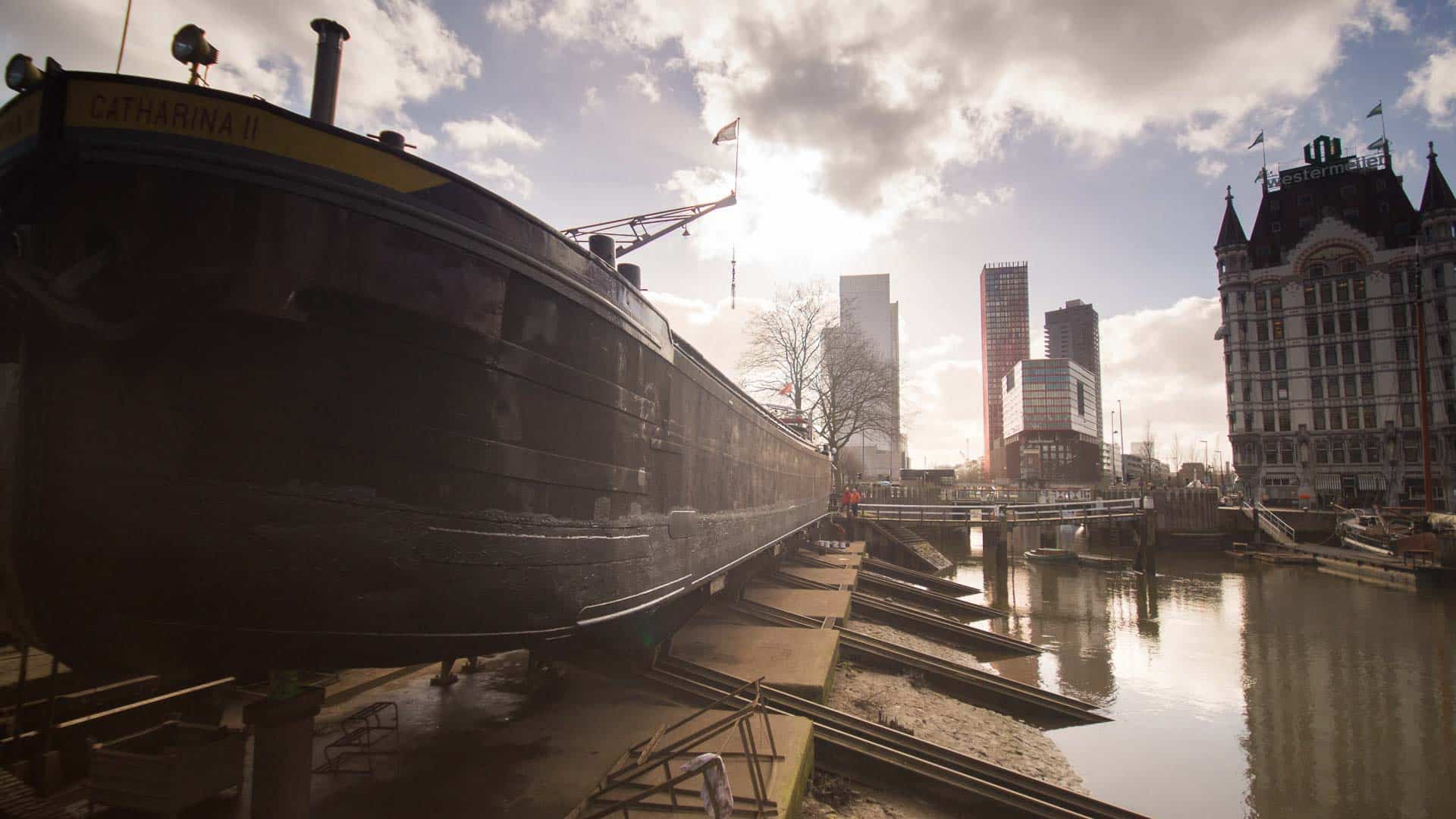 O barco chamado “Catharina II” repousa no cais perto da água em uma área urbana, com edifícios modernos erguendo-se sob um céu nublado, simbolizando as vastas oportunidades de importação no horizonte à medida que nos aproximamos de 2025.
