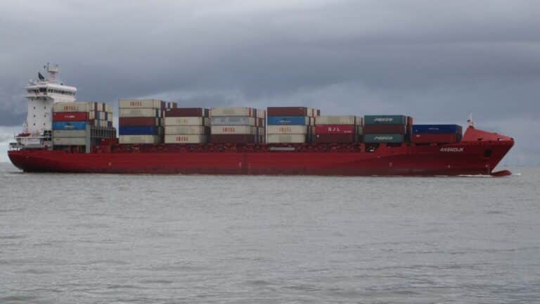 Navio de carga no mar sob um céu nublado, carregado com contêineres empilhados, navegando estrategicamente para reduzir os custos de frete até 2025.