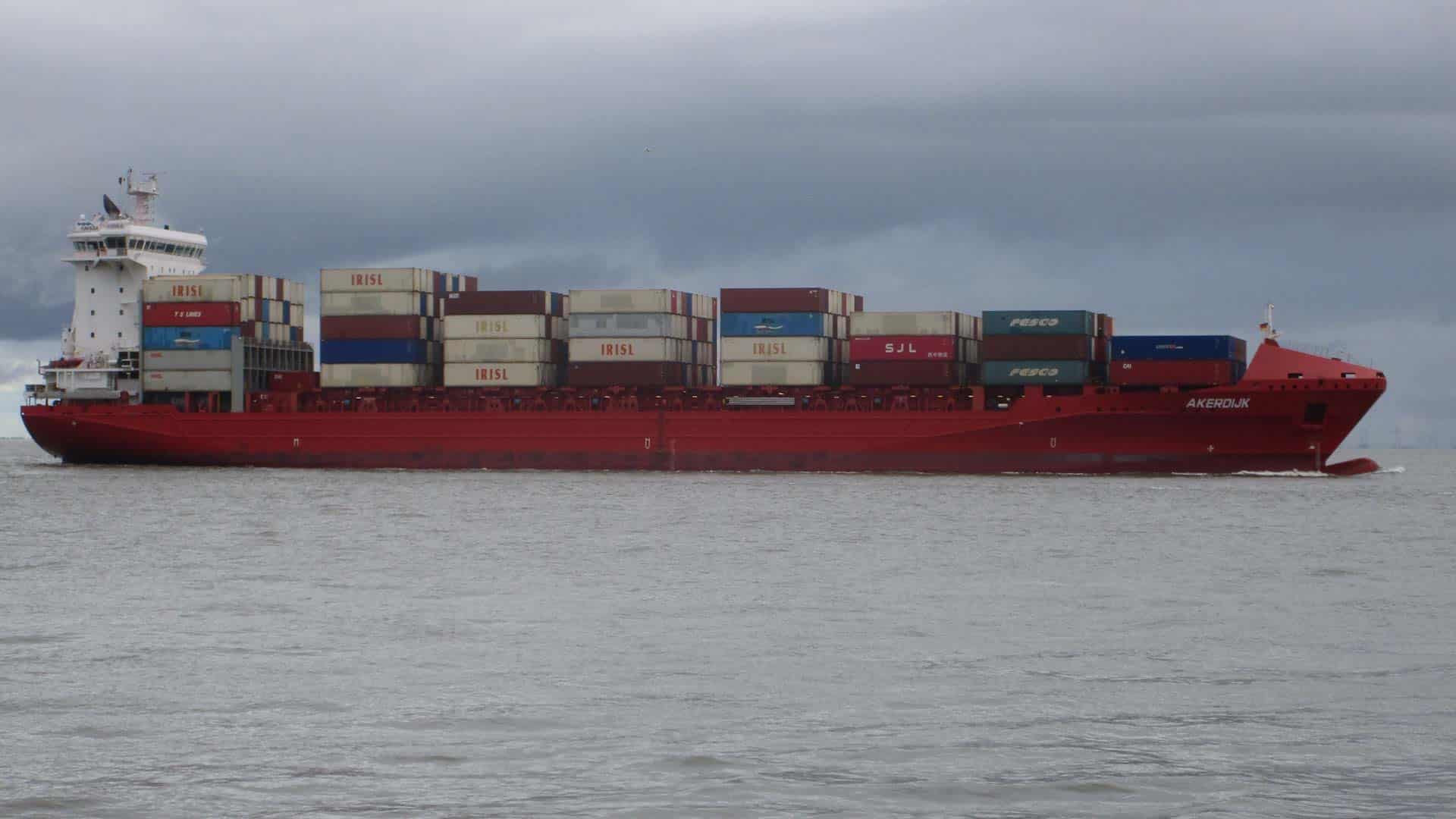 Navio de carga no mar sob um céu nublado, carregado com contêineres empilhados, navegando estrategicamente para reduzir os custos de frete até 2025.