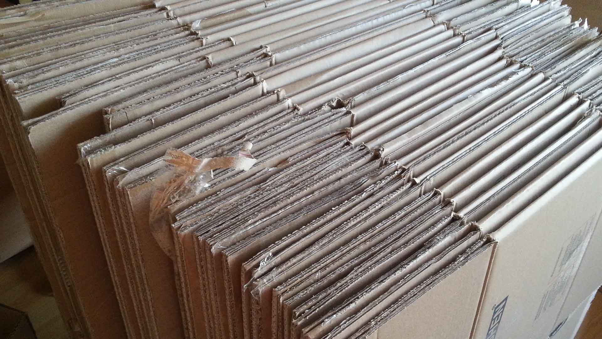 Pilhas de caixas de papelão achatadas e organizadas em fileiras organizadas, prontas para acompanhar sua jornada no guia de importação rumo ao futuro da eletrônica 2025.