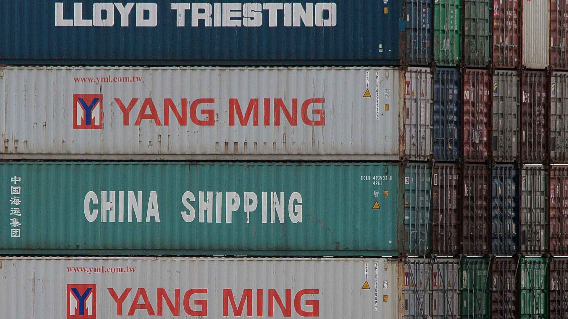 Pilhas de contêineres de transporte com logotipos como "LLOYD TRIESTINO", "YANG MING" e "CHINA SHIPPING" são um testemunho das conexões comerciais globais. Até 2025, a China pretende aprimorar a Inspeção de Produtos, garantindo que as verificações de qualidade sejam perfeitamente integradas a este movimentado centro.