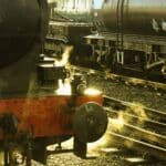 Uma locomotiva a vapor avança ruidosamente pelos trilhos da ferrovia, liberando nuvens de vapor enquanto os vagões se aquecem na luz quente do sol. É uma reminiscência da dança intrincada entre as commodities de importação da China e as indústrias locais de gravatas, cada uma criando uma tapeçaria de história e progresso.