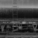 Uma imagem em preto e branco da lateral de um trem com marcações enferrujadas e rodas visíveis, lembrando relíquias em um catálogo da Importação de Relógios. Duas estrelas são pintadas na lateral.