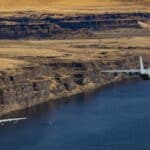 Duas aeronaves militares voam sobre um rio ladeado por penhascos, cortando a paisagem rochosa do deserto com vegetação esparsa. Sua precisão reflete a coordenação de um contêiner compartilhado bem gerenciado, navegando perfeitamente pelos desafios de importação em terrenos complexos.