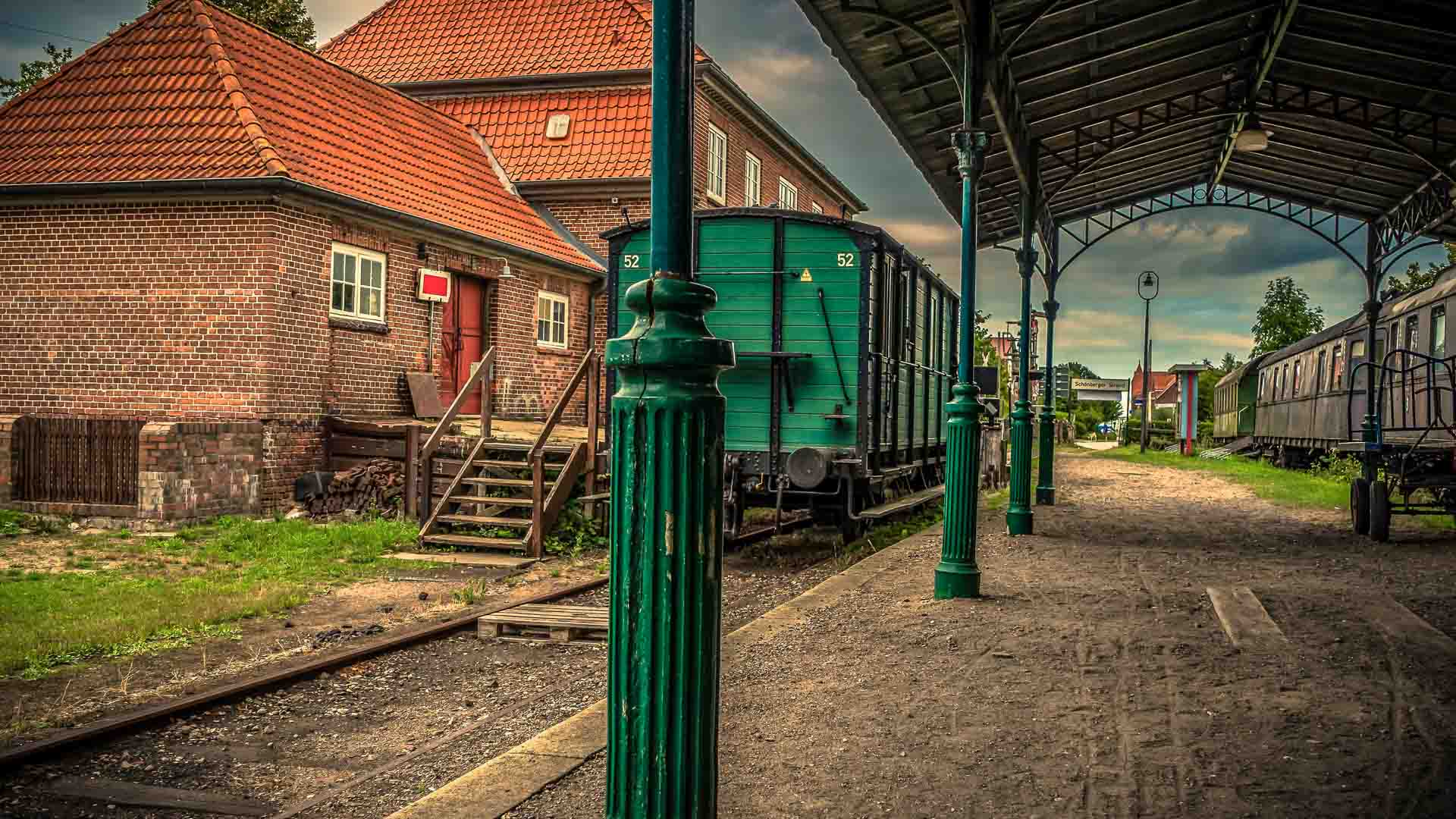 A estação de trem vintage, com vagões de carga verdes e prédios de tijolos, evoca um charme atemporal sob sua plataforma. À medida que o céu nublado paira sobre a cabeça, parece uma reminiscência de centros movimentados como os da China.