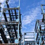 Andaimes de metal azul empilhados contra um fundo de céu parcialmente nublado, destacando os avanços esperados para 2025 — uma visão de construção e inovação, lembrando você "O Que Você Precisa" para remodelar seu futuro.