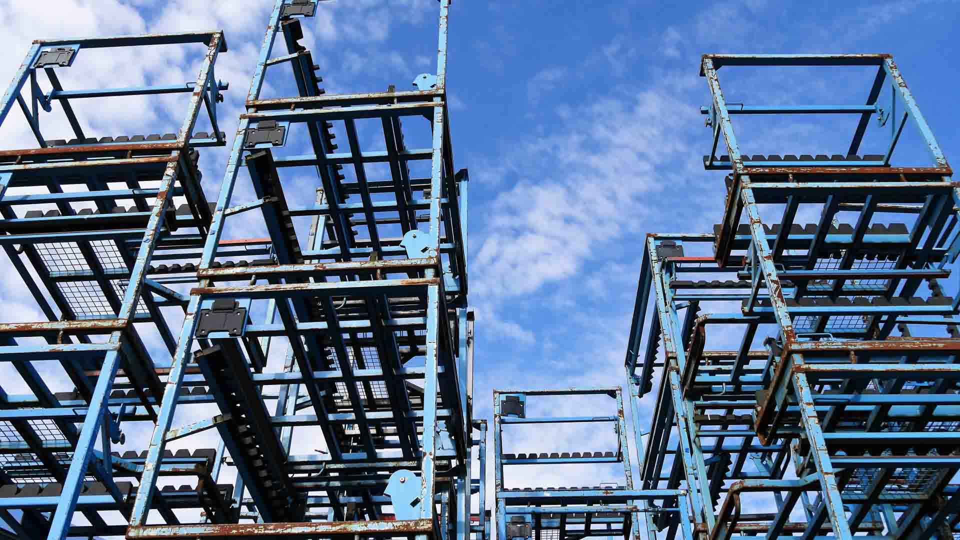 Andaimes de metal azul empilhados contra um fundo de céu parcialmente nublado, destacando os avanços esperados para 2025 — uma visão de construção e inovação, lembrando você "O Que Você Precisa" para remodelar seu futuro.