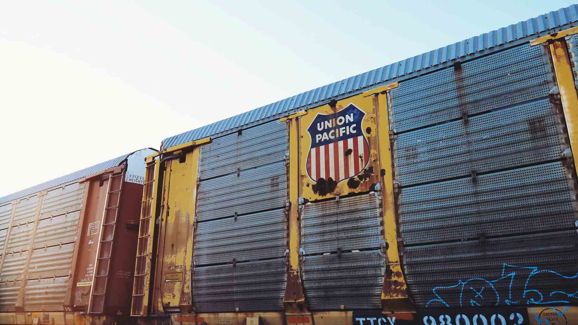 Os vagões de carga da Union Pacific, adornados com um logotipo de escudo vermelho e azul, transportam produtos importados da China, destacando um fluxo internacional de mercadorias.