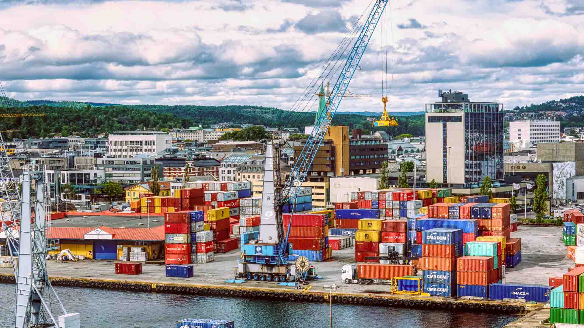 Um movimentado porto de embarque com contêineres de carga coloridos empilhados, um enorme guindaste e prédios ao fundo reflete a atividade vibrante de um centro importador, categorizado eficientemente pela CNAE para operações simplificadas.
