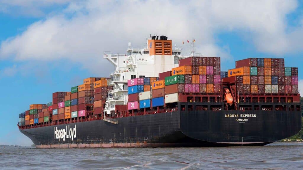 Um grande navio de carga, carregado com Produtos da China, navega sob um céu parcialmente nublado, com seu convés abarrotado de contêineres coloridos que prometem qualidade.