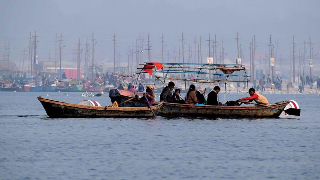 Um grupo de pessoas em um barco de madeira navega pelo rio, personificando a dedicação semelhante à Regra das 10 Mil Horas. Mais alguns barcos flutuam por perto, importando uma sensação de tranquilidade contra a costa distante suavemente delineada ao fundo.