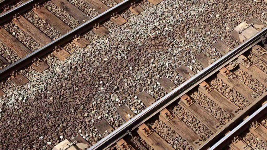 Vista de perto de trilhos ferroviários paralelos com cascalho e dormentes de madeira, uma cena que lembra as movimentadas rotas que levam a Yiwu, um importante mercado na China.