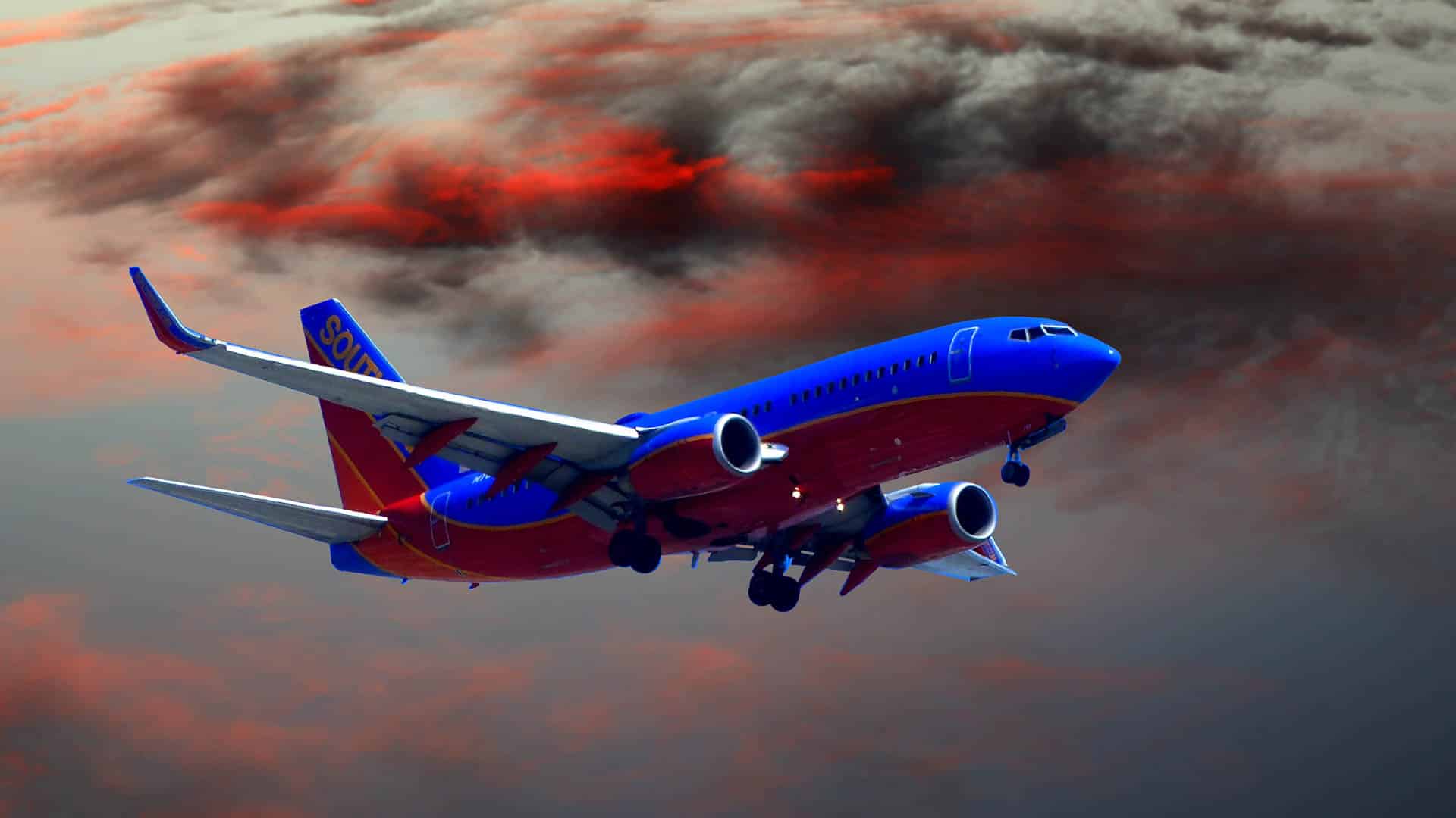 Um avião comercial com cores azul e vermelha voa contra um céu dramático, sua ascensão tão vibrante quanto um processo de sublimação pintando nuvens escuras e vermelhas na tela dos céus.