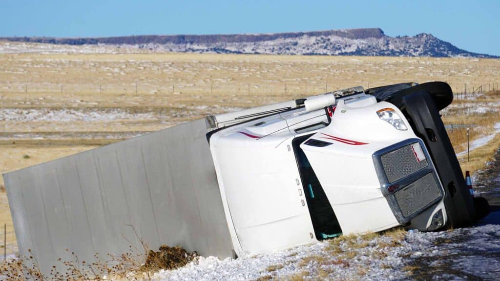 Um caminhão branco tombado em uma estrada coberta de neve em 2025, com um campo aberto e uma mesa ao fundo, enquanto a Grandes Importadores se esforça para competir em condições desafiadoras.