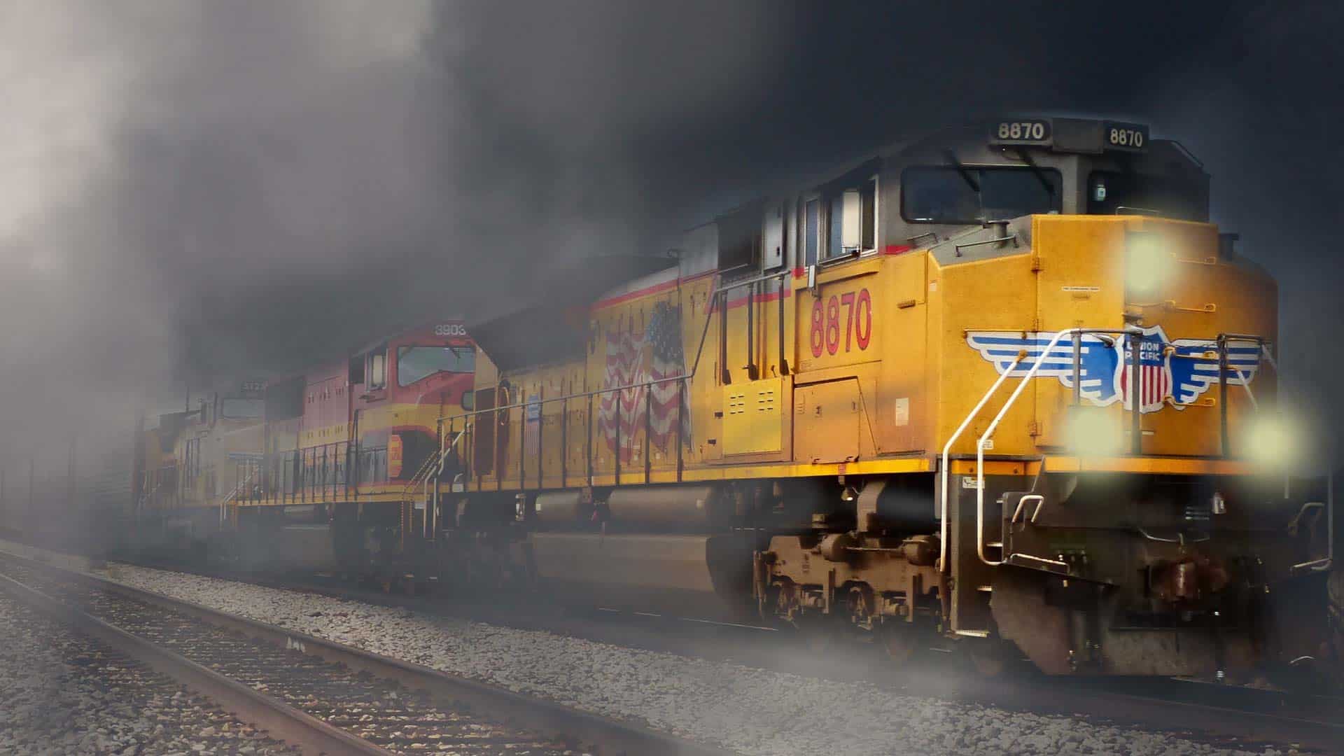 Um trem de carga amarelo viaja sobre trilhos em meio à fumaça densa, com um logotipo e número 8670 visíveis na locomotiva da frente, uma reminiscência de produtos que você frequentemente encontra ao optar por importar e vender produtos.