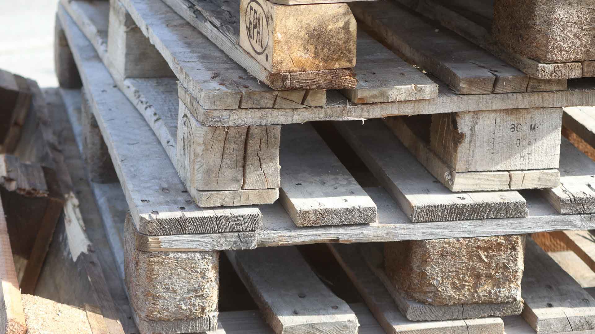 Uma pilha de paletes de madeira desgastadas, mostrando sinais de desgaste e idade, está pronta para desempenhar um papel crucial na melhoria da eficiência logística.